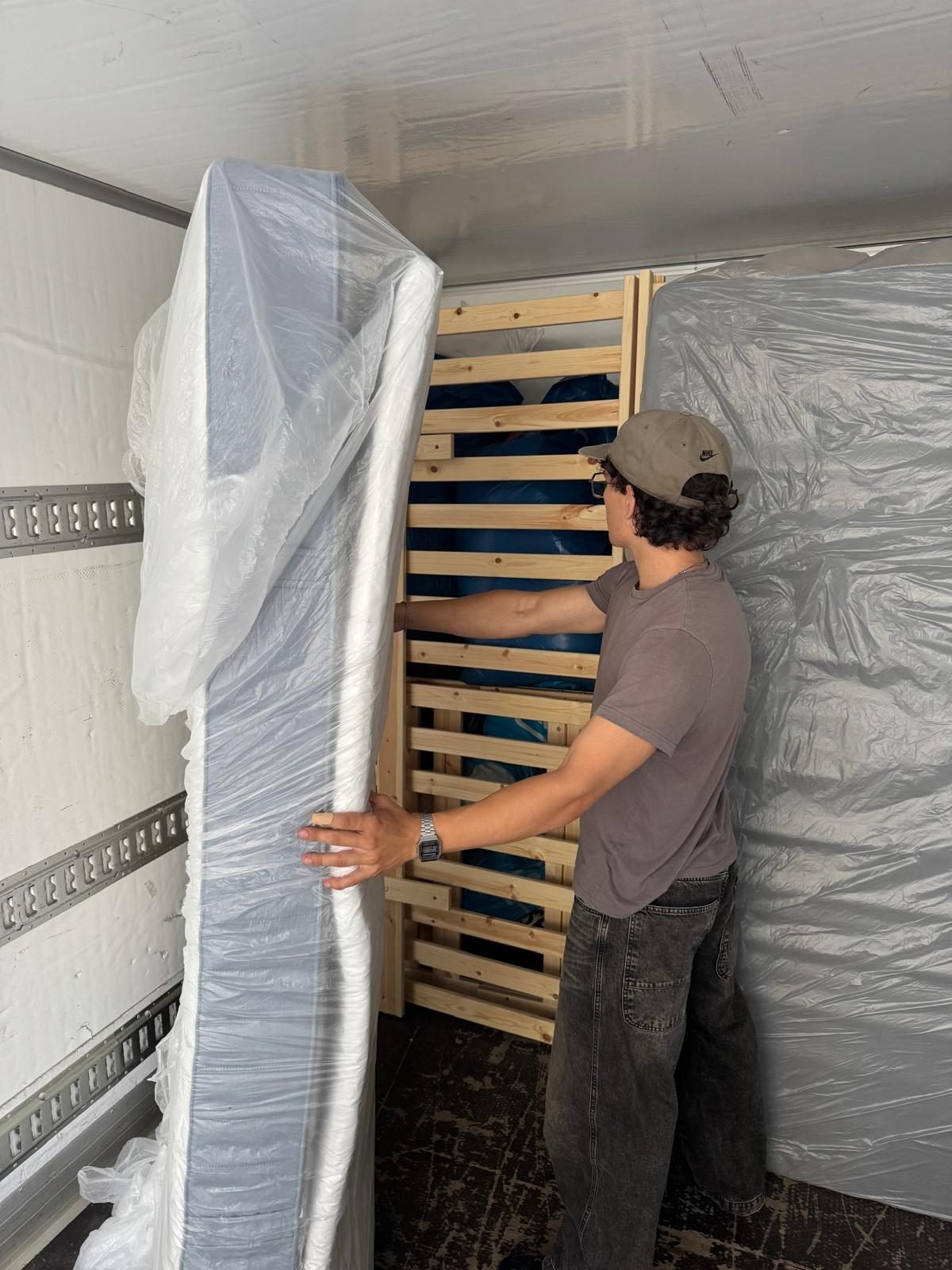 A mattress being carefully loaded and secured inside the truck