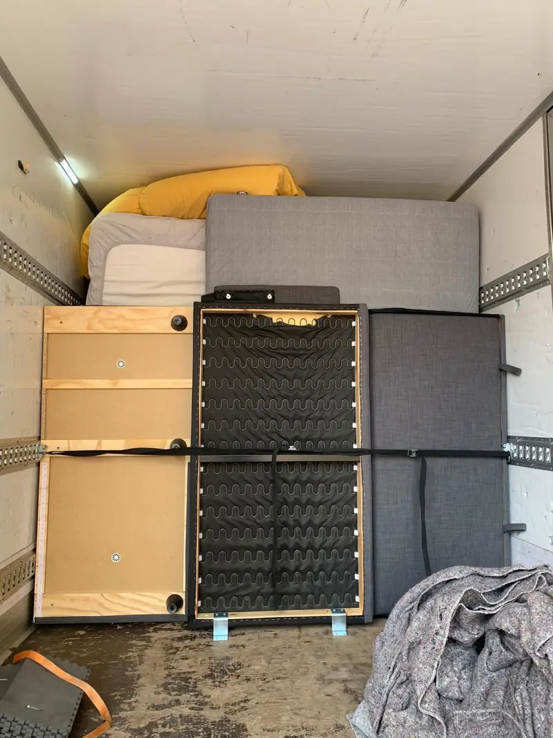 Furniture parts and a sofa secured with straps in the truck.