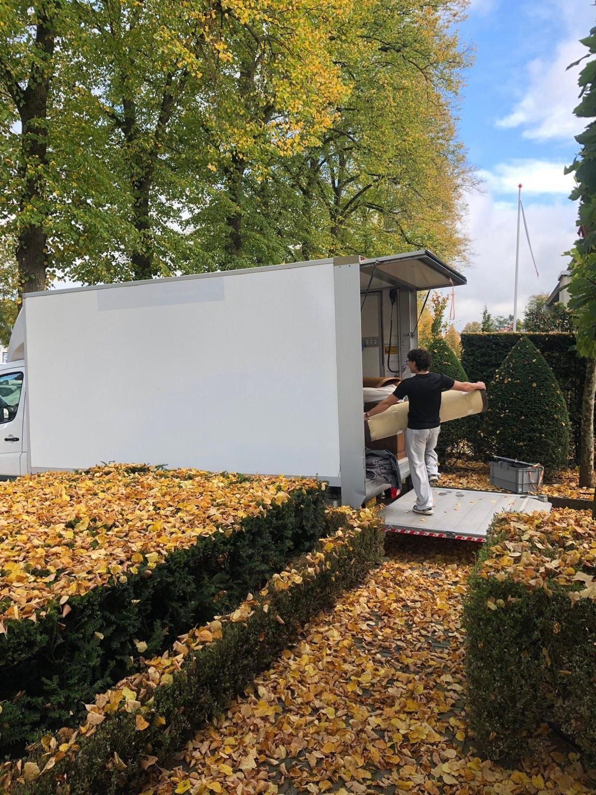 Mover carrying a rolled-up carpet into the truck